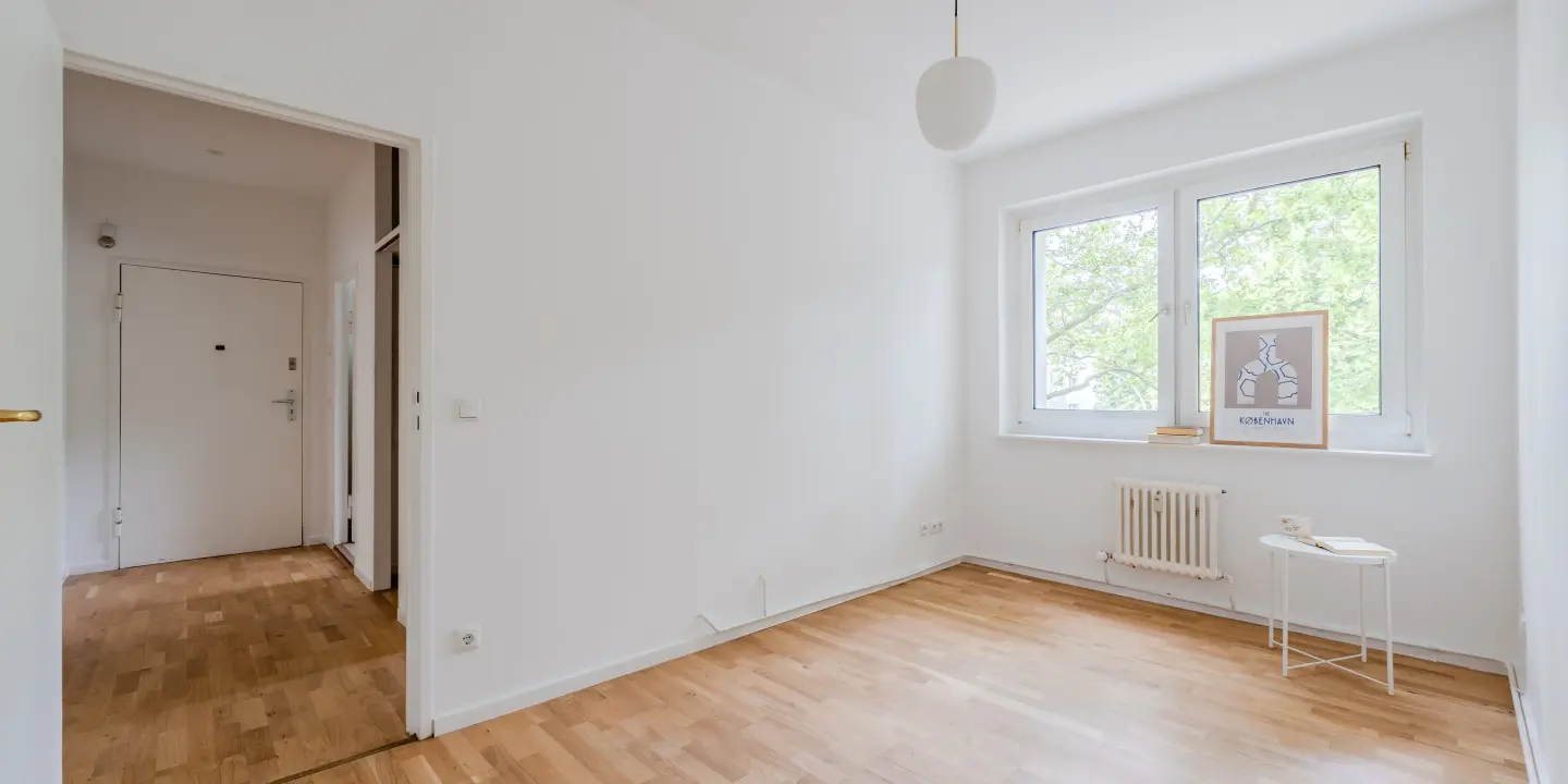Heller Wohnbereich mit großem Fenster und Parkett